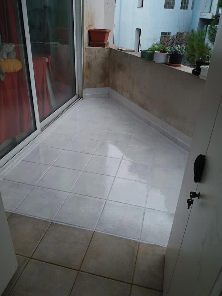 Λευκή στεγανωτική επίστρωση πάνω στα πλακάκια ενός μπαλκονιού