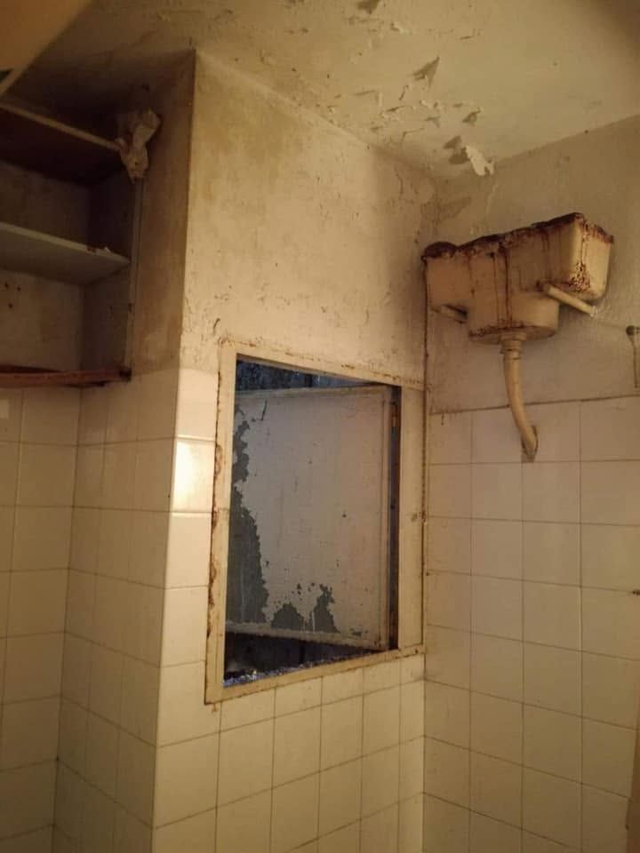 Παλιό καζανάκι και ξεφλουδισμένοι τοίχοι πάνω από τα πλακάκια
