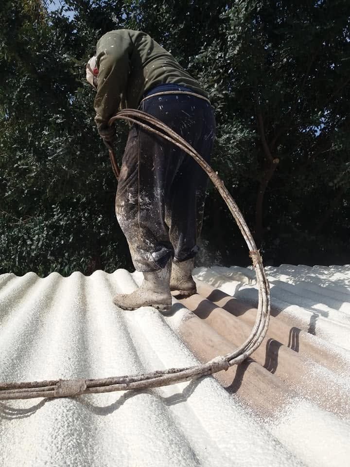 A worker spraying foam onto the corrugated sheets