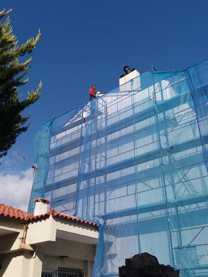 Η πολυκατοικία καλυμμένη με σκαλωσιά και μπλε δίχτυ