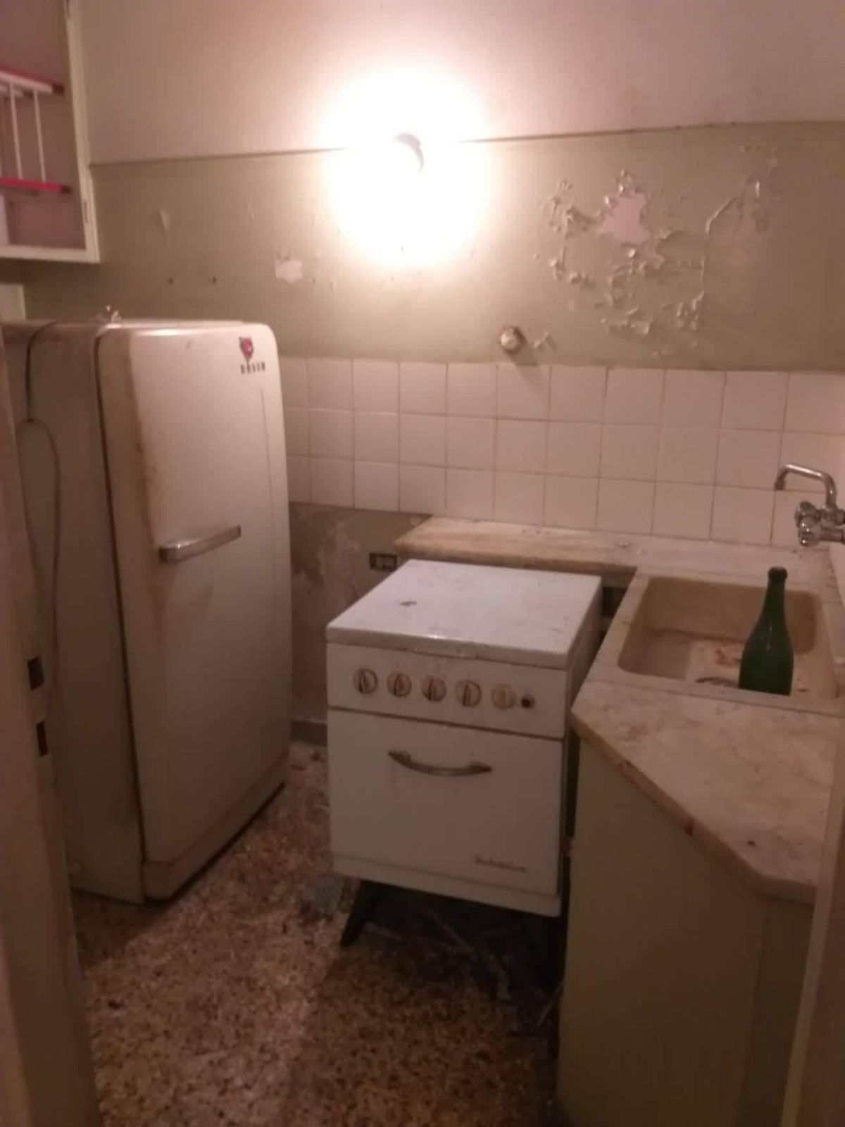 Η παλιά κουζίνα με ξεφτισμένο σοβά πάνω από τα πλακάκια