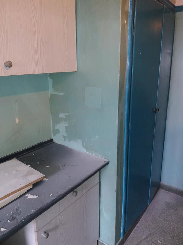 A worn wall next to the blue cupboard