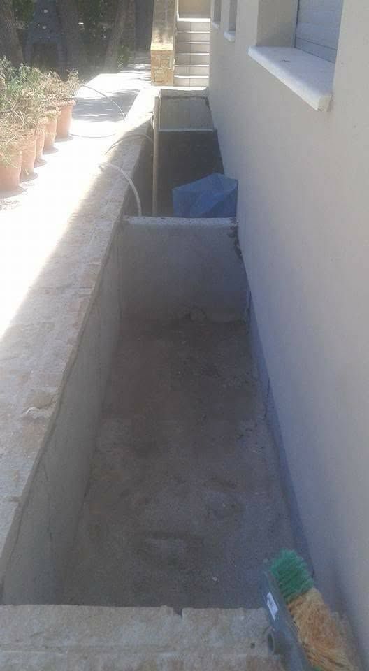 Η μακριά ζαρντινιέρα δίπλα στον τοίχο του σπιτιού, άδεια