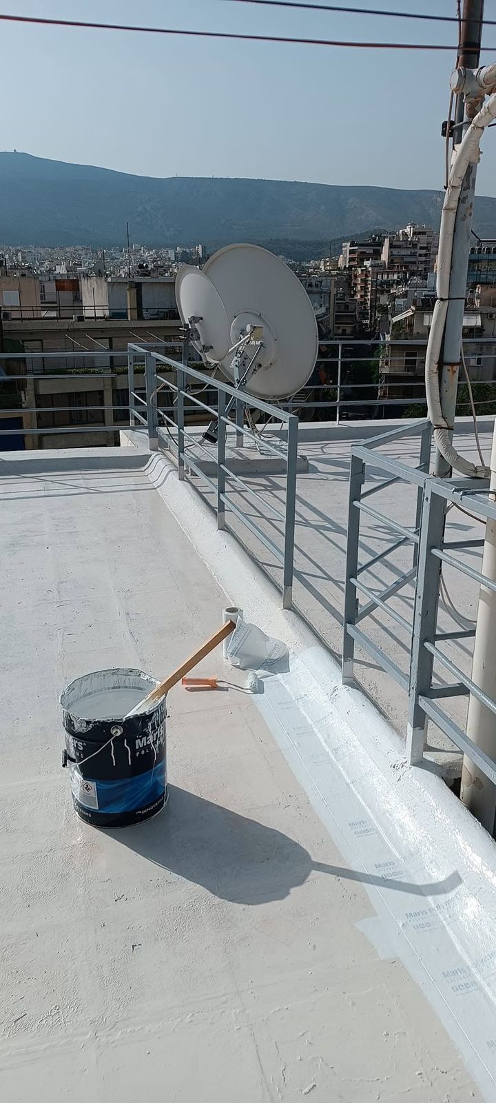 Δοχείο και ρολό δίπλα στο τοιχίο κάτω από τα κάγκελα