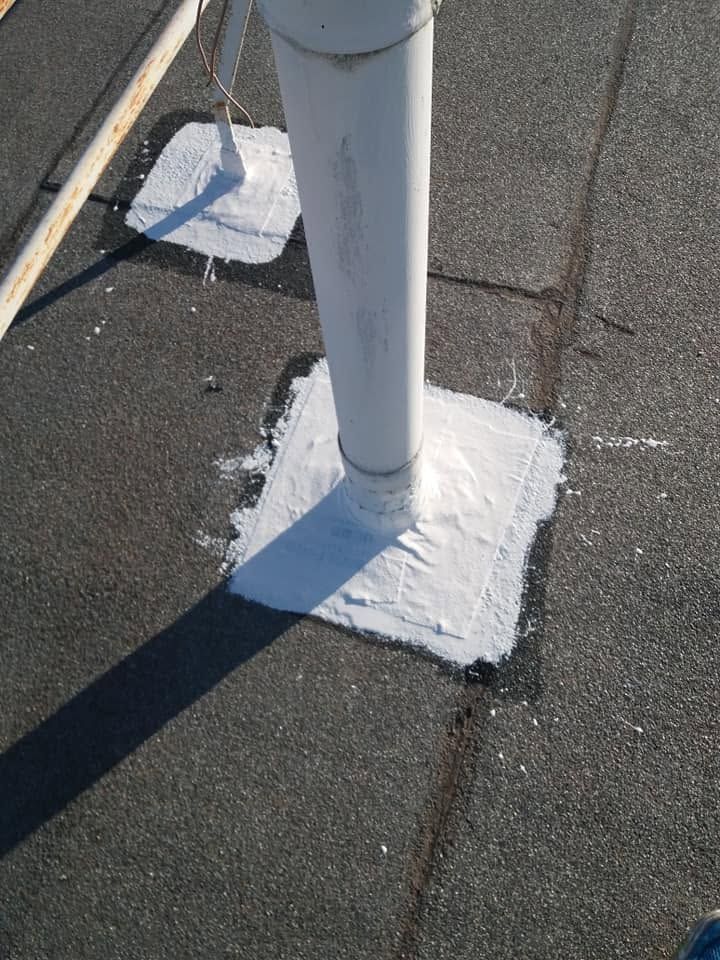 A white pipe with its base sealed on the roof