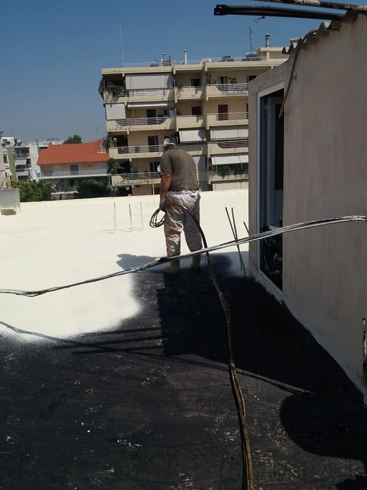 A worker spraying polyurethane foam over the primer