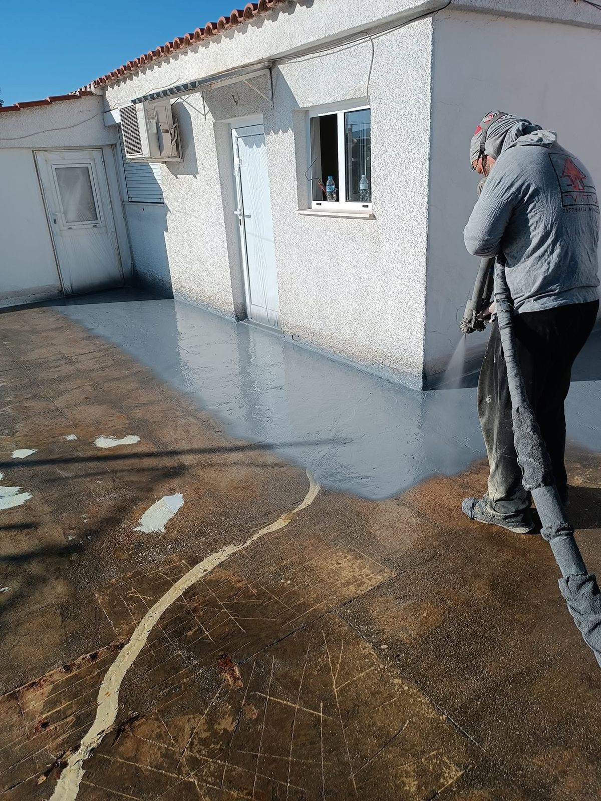 Τεχνίτης ψεκάζει το στεγανωτικό με μάνικα